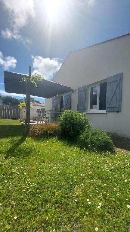 une maison avec un parasol bleu dans la cour dans l'établissement Au cœur de l'ile d'Oléron, à Dolus-d'Oléron