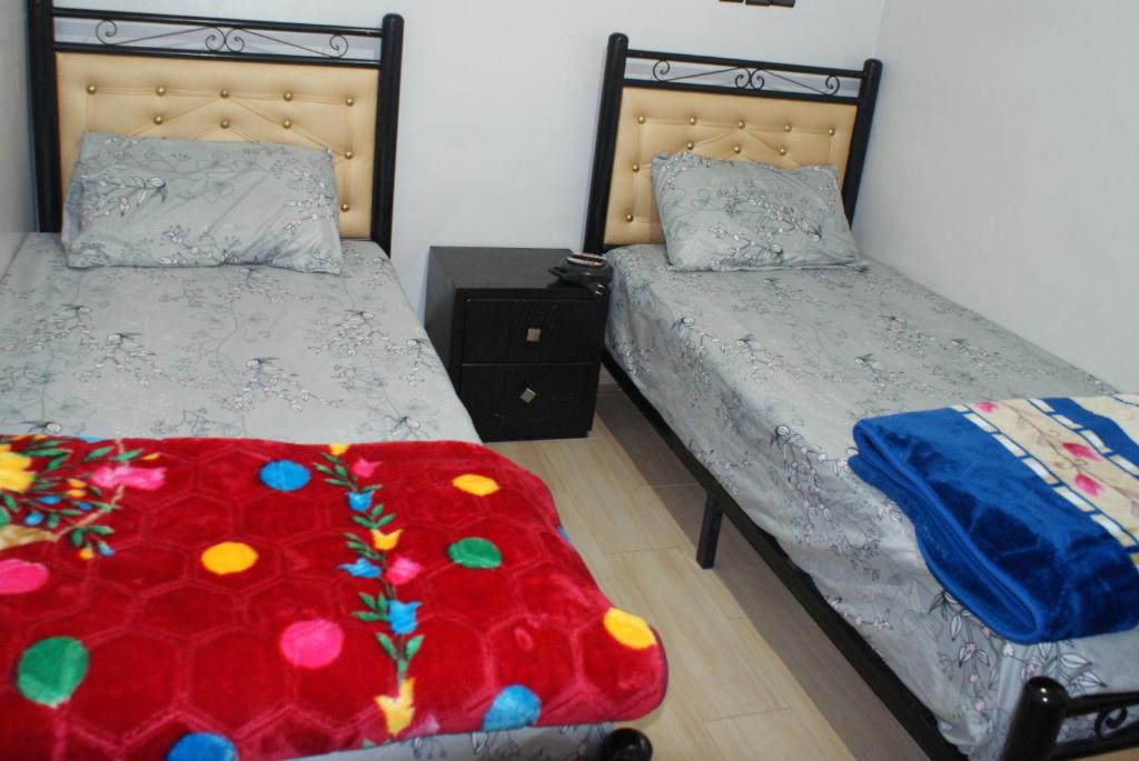a bedroom with two beds and a red blanket at Magnifique chambre à prix inedit in Agadir