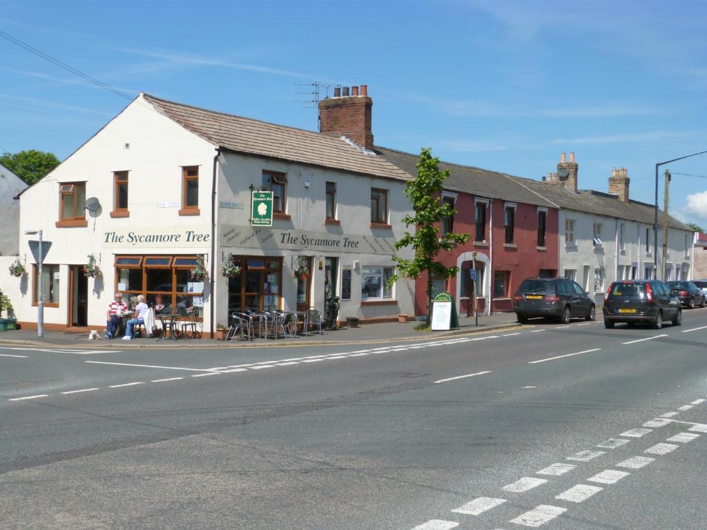 uma rua com um edifício ao lado de uma estrada em The Sycamore Tree em Longtown