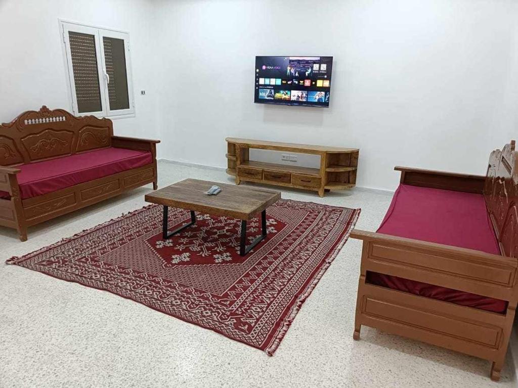 a living room with couches and a table and a tv at Maison Chebbi in Tozeur