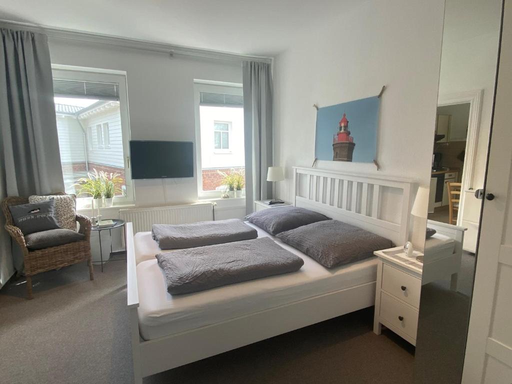 a bedroom with a bed and a chair and windows at Haus AchternDiek Strandvogel in Dahme