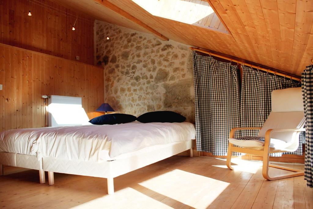 ein Schlafzimmer mit einem Bett und einem Stuhl in einem Zimmer in der Unterkunft VALRELEY, chambres et table d'hôtes eco-friendly avec bain nordique au sud du massif du Jura in Champagne-en-Valromey