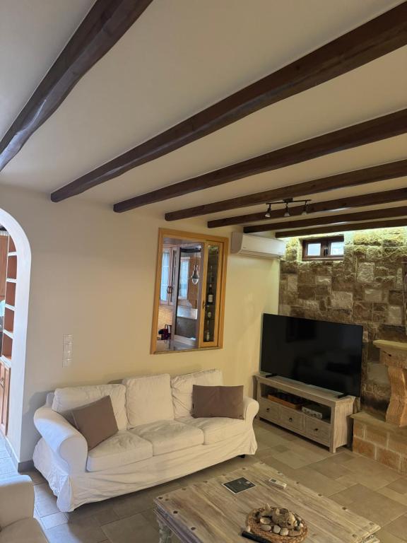 a living room with a white couch and a television at Flash House in Spetses