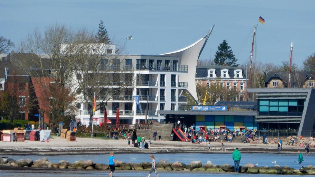 people standing in the water in front of a building at Apartment 29 "Heimathafen 29", Apartmenthaus Hafenspitze, Blickrichtung InnenstadtBinnenhafen in Eckernförde
