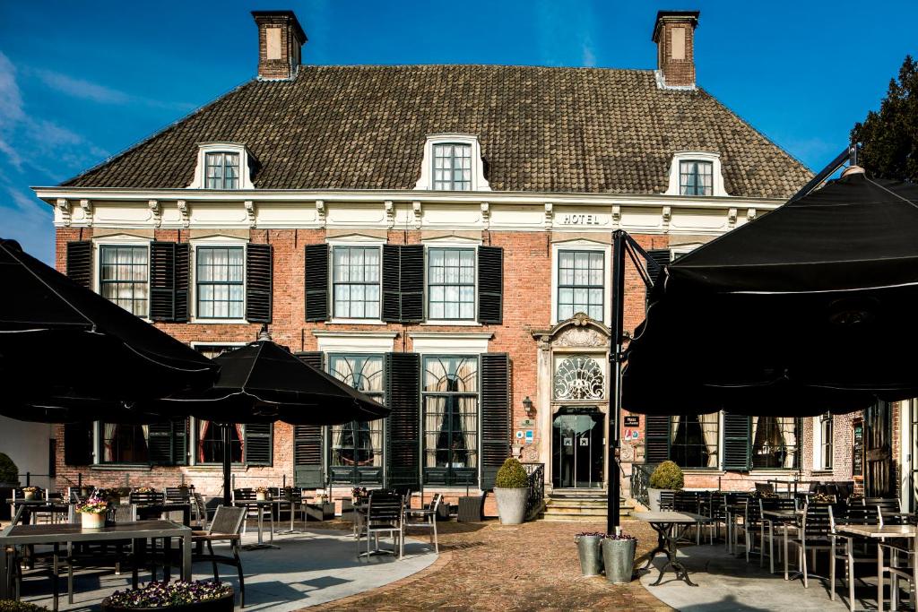 een gebouw met tafels en parasols ervoor bij Hampshire Hotel - 's Gravenhof Zutphen in Zutphen