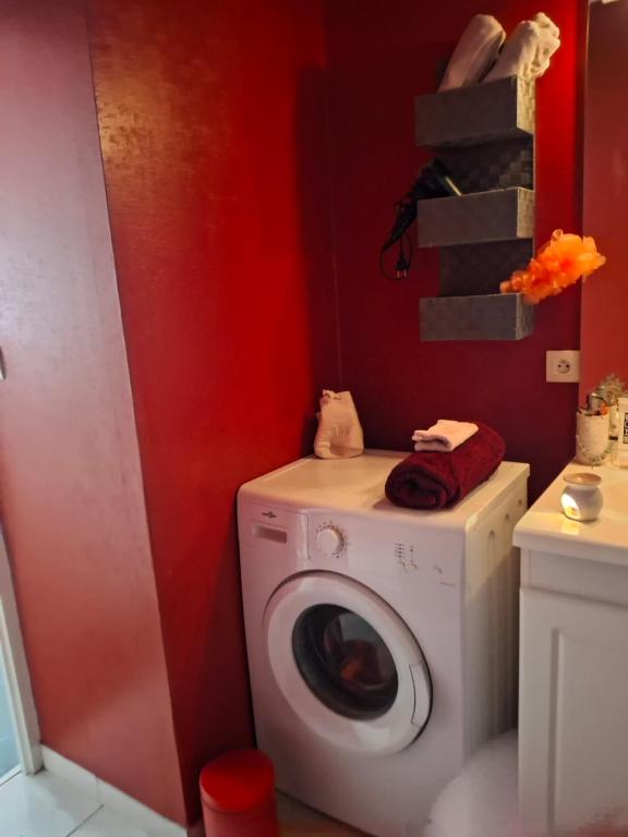 - un lave-linge dans une salle de bains dotée d'un mur rouge dans l'établissement Le plaisir du calme, à Limoges