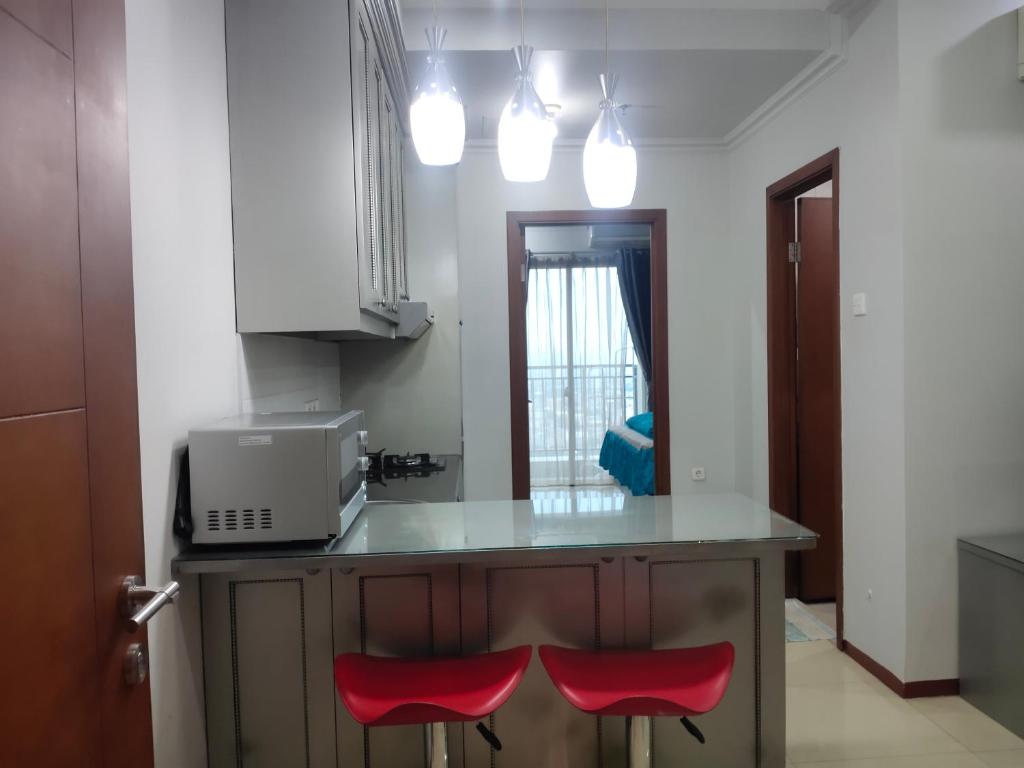 una cucina con un bancone con due sedie rosse di Sewa Apartemen Thamrin Residences a Giacarta