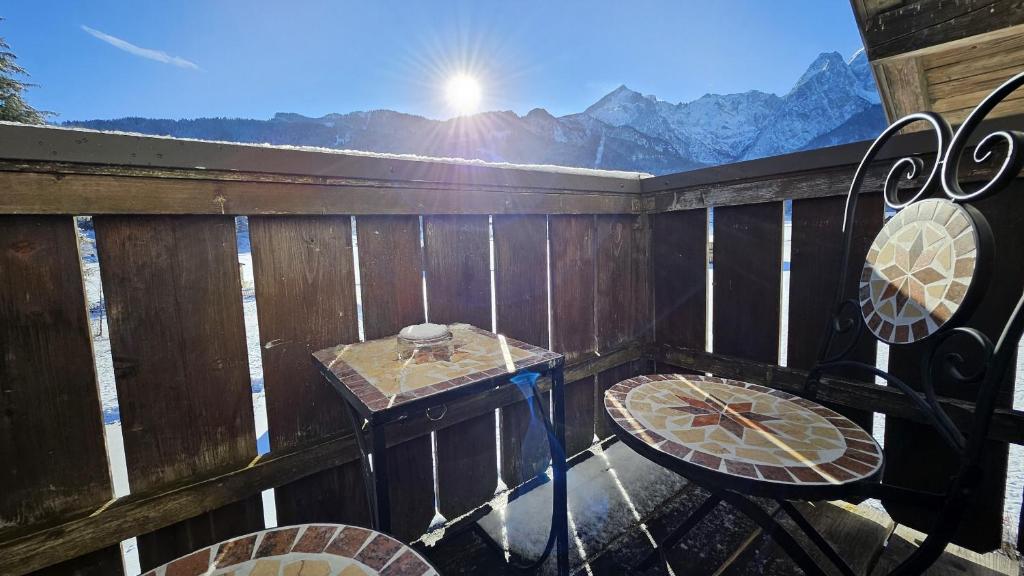 balcone con tavolo, sedie e vista sulle montagne. di Haus Kreuzeckwiese - FeWo-Waxenstein - Studio Appartment a Garmisch-Partenkirchen
