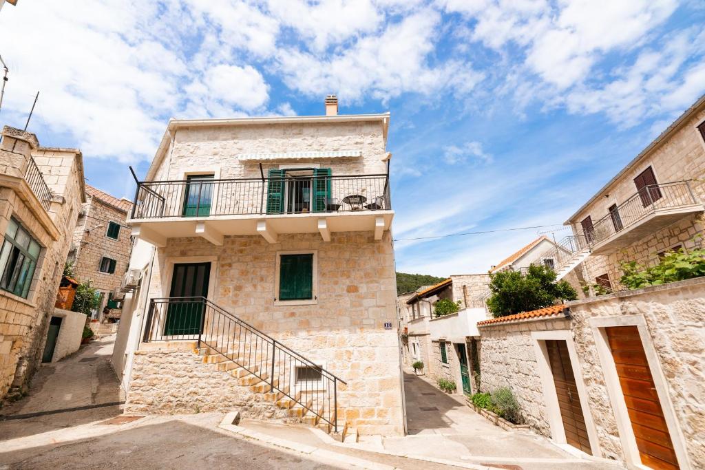 a stone house with a balcony on a street at Apartments by the sea Pucisca, Brac - 23445 in Pučišća