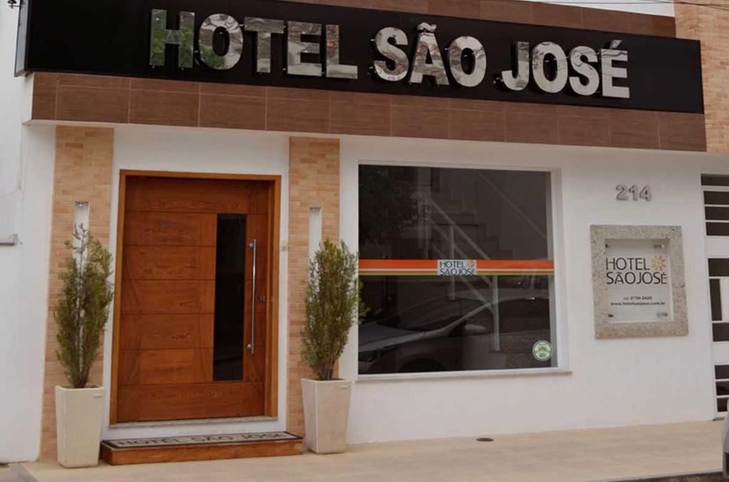 a hotel sao jose building with a door and two plants at Hotel São José in São Fidélis