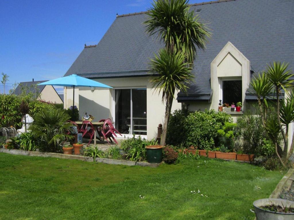 a house with a table and a blue umbrella at Holiday Home in Pleubian near Kermagen Beach in Pleubian