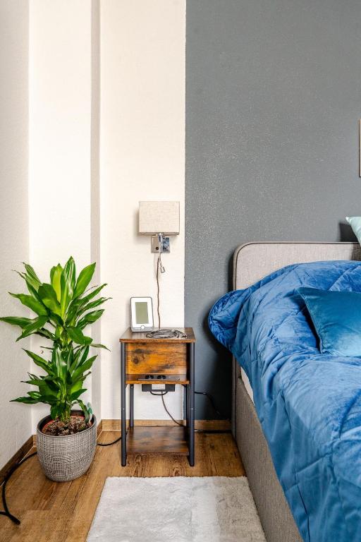 a bedroom with a blue bed and a table with a plant at Vienna Garden Bungalow in Langenzersdorf