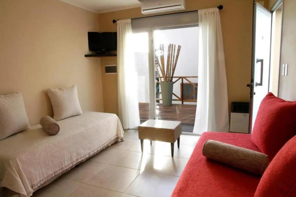 sala de estar con sofá y silla roja en Departamentos Recalada Suites, en Monte Hermoso