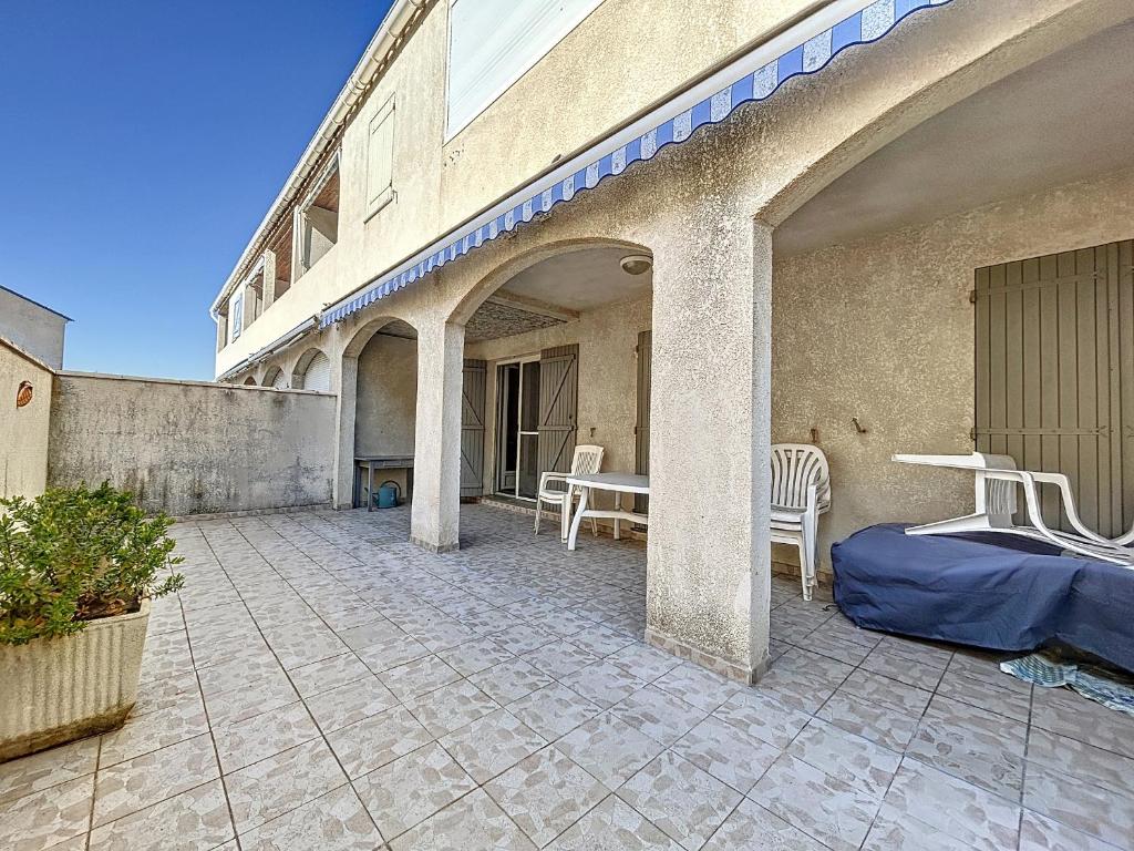 un patio avec des chaises et une table dans un bâtiment dans l'établissement Appartement 3 pièces, terrasse ensoleillée, climatisation, stationnement, 4 pers - FR-1-475-155, à Saintes-Maries-de-la-Mer