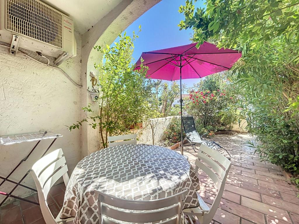 - une table et des chaises avec un parasol violet sur la terrasse dans l'établissement Studio pour 4 Pers., Climatisé, Animaux Bienvenus - FR-1-475-207, à Saintes-Maries-de-la-Mer