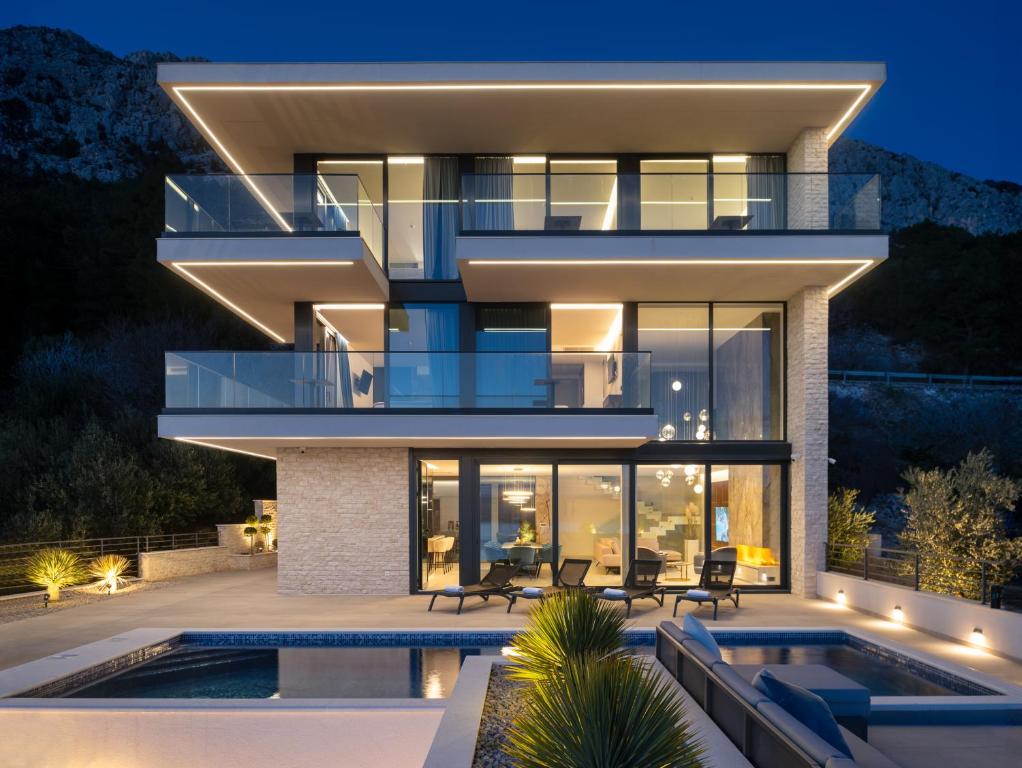 a modern house with a swimming pool at night at Luxury Villa Hedonia in Brela