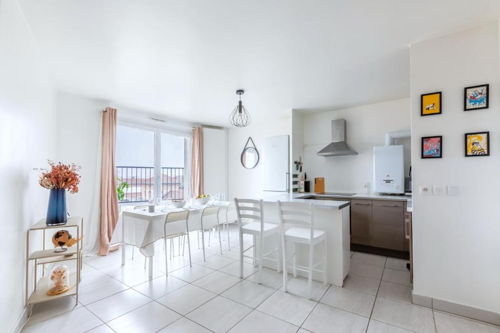 サン・トゥアンにあるMagnifique vue sur la Tour Eiffel - Paris 10mn - Parking privé gratuit - métro 2min - balconの白いキッチン(テーブル、椅子付)
