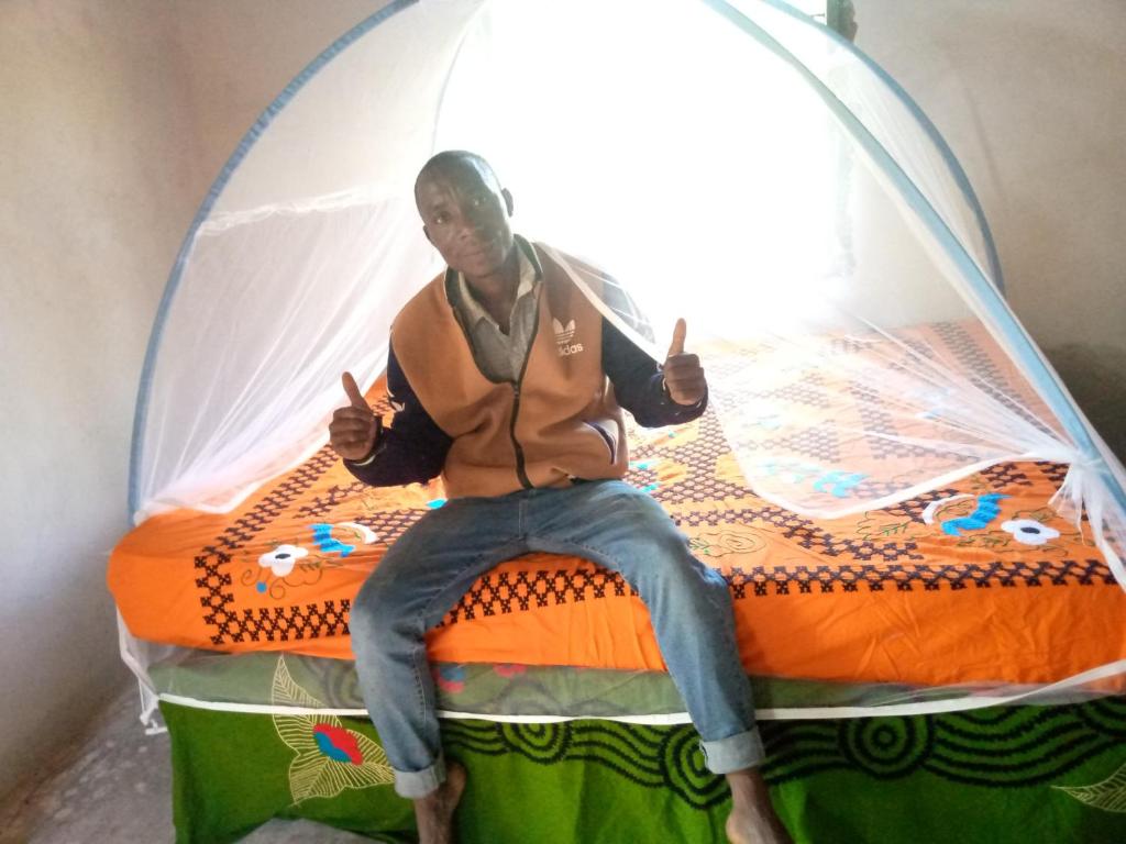 Tongwe Cultural Heritage Center في Katumbi: امرأة تجلس على سرير في خيمة فقاعات