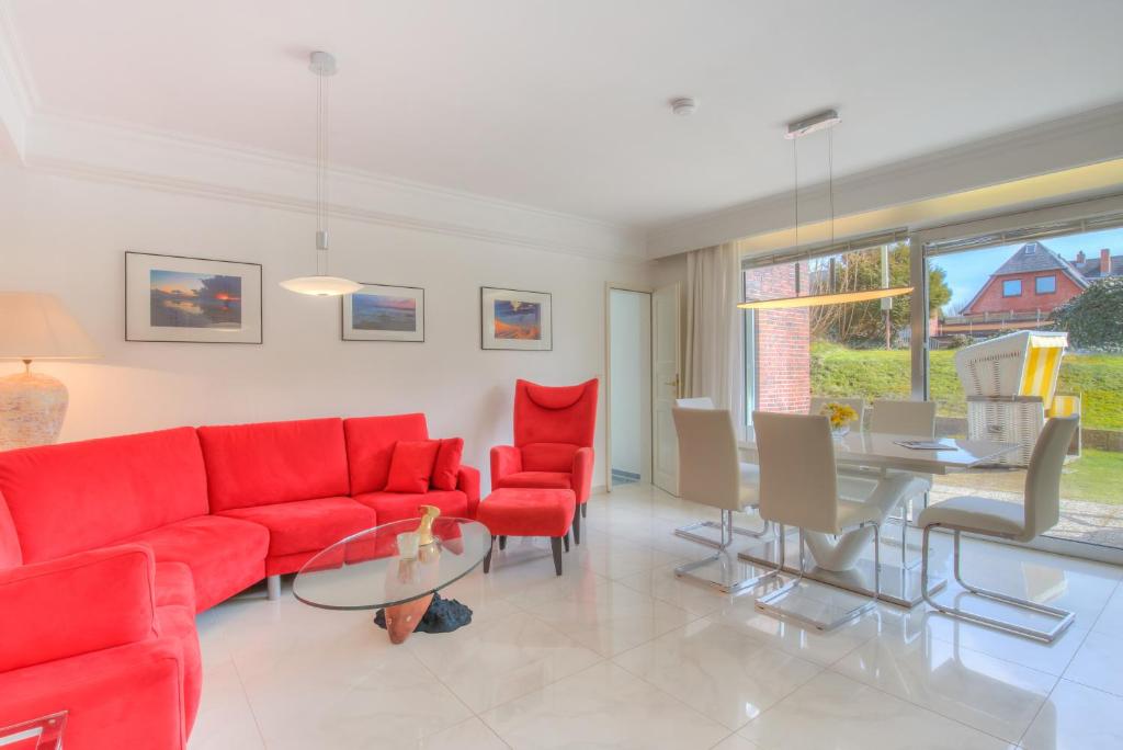 a living room with a red couch and a table at Windeby 1T in Wenningstedt