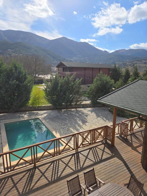 a deck with chairs and a pool with mountains in the background at Chalet Stiga Kalavrita - Maisonettes in Kalavrita