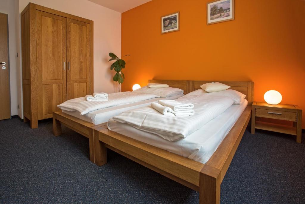 2 łóżka pojedyncze w pokoju z pomarańczową ścianą w obiekcie Hotel Lions Plzen w Pilznie
