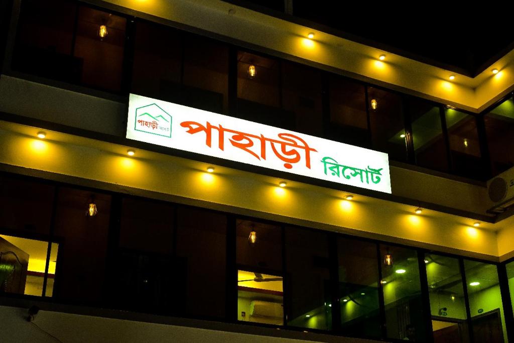 un cartello sul lato di un edificio con luci di Pahari Resort a Sreemangal