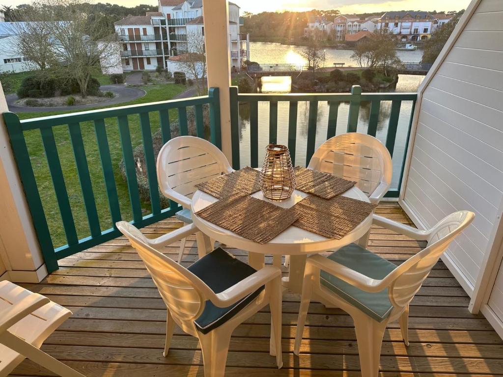 ein Tisch und Stühle auf einem Balkon mit Aussicht in der Unterkunft Fleurs du lac studio 2 adultes et 2 enfants avec terrasse vue sur le lac et accès parc aquatique gratuit in Talmont