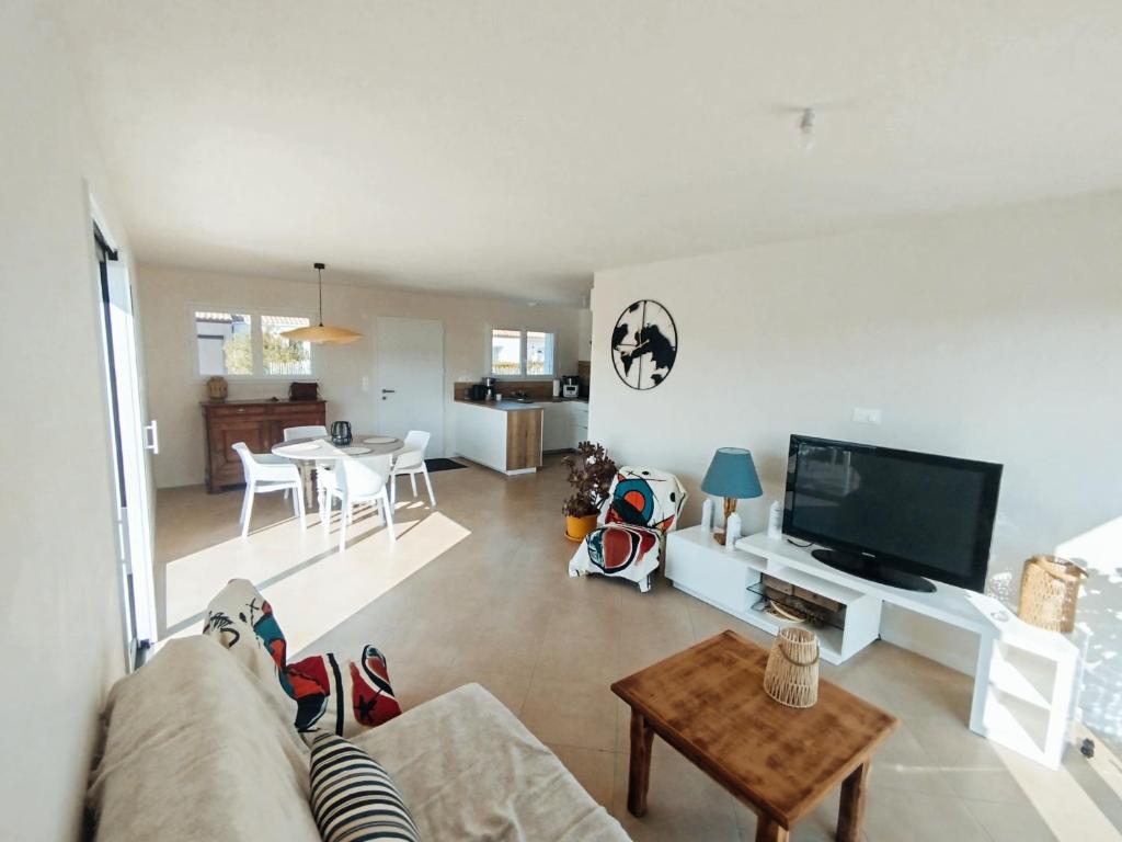 un salon avec un canapé, une télévision et une table dans l'établissement Ladybird Maison 4 à 5 pers climatisée, à Longeville-sur-Mer