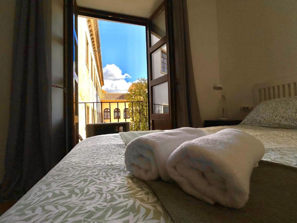 a pile of towels sitting on a bed with a window at Edén Luxury Suites in Granada