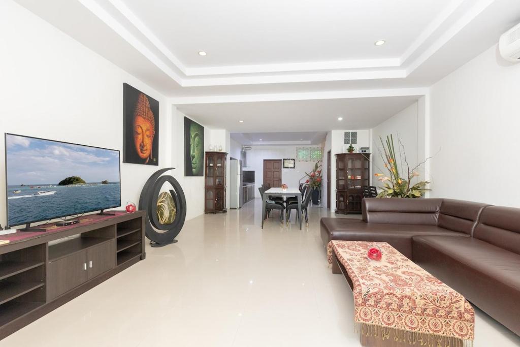 un soggiorno con divano e TV a schermo piatto di Peaceful House in Rawai, Phuket a Phuket