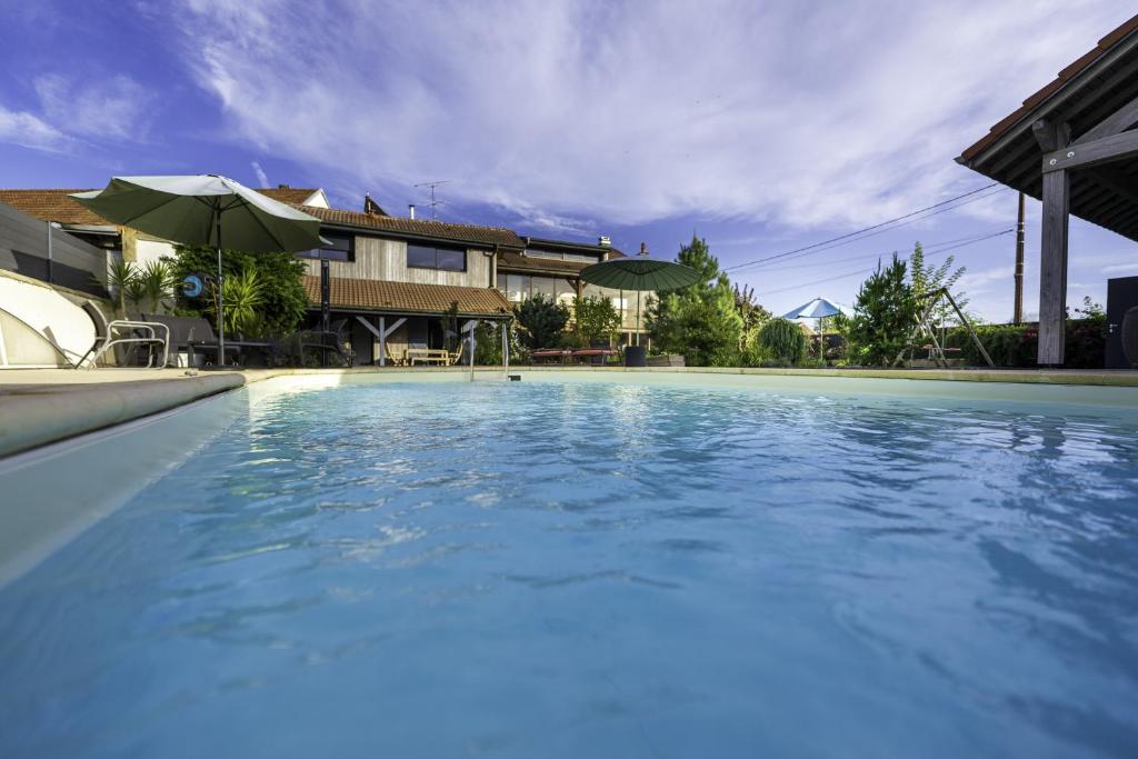 una piscina con acqua blu davanti a una casa di Appartement cosy et chaleureux 6 personnes a La Baffe
