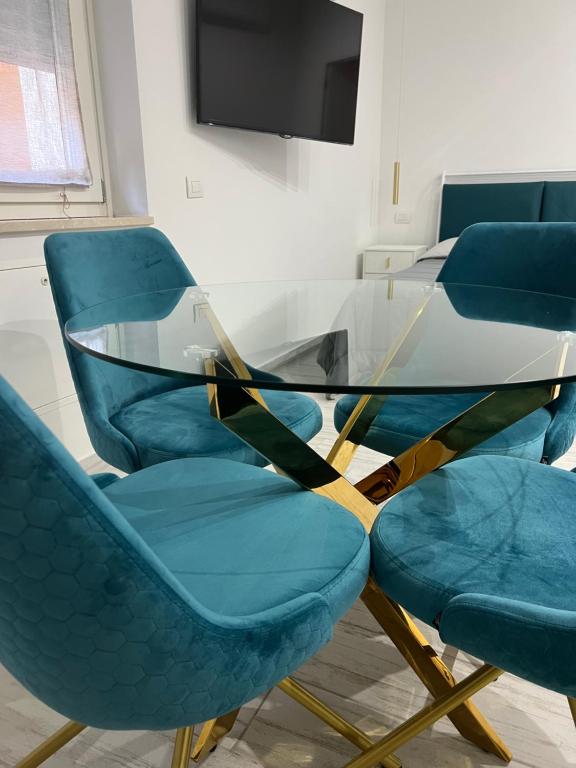 a glass table with four blue chairs and a television at Casa nel vicolo in Montichiari
