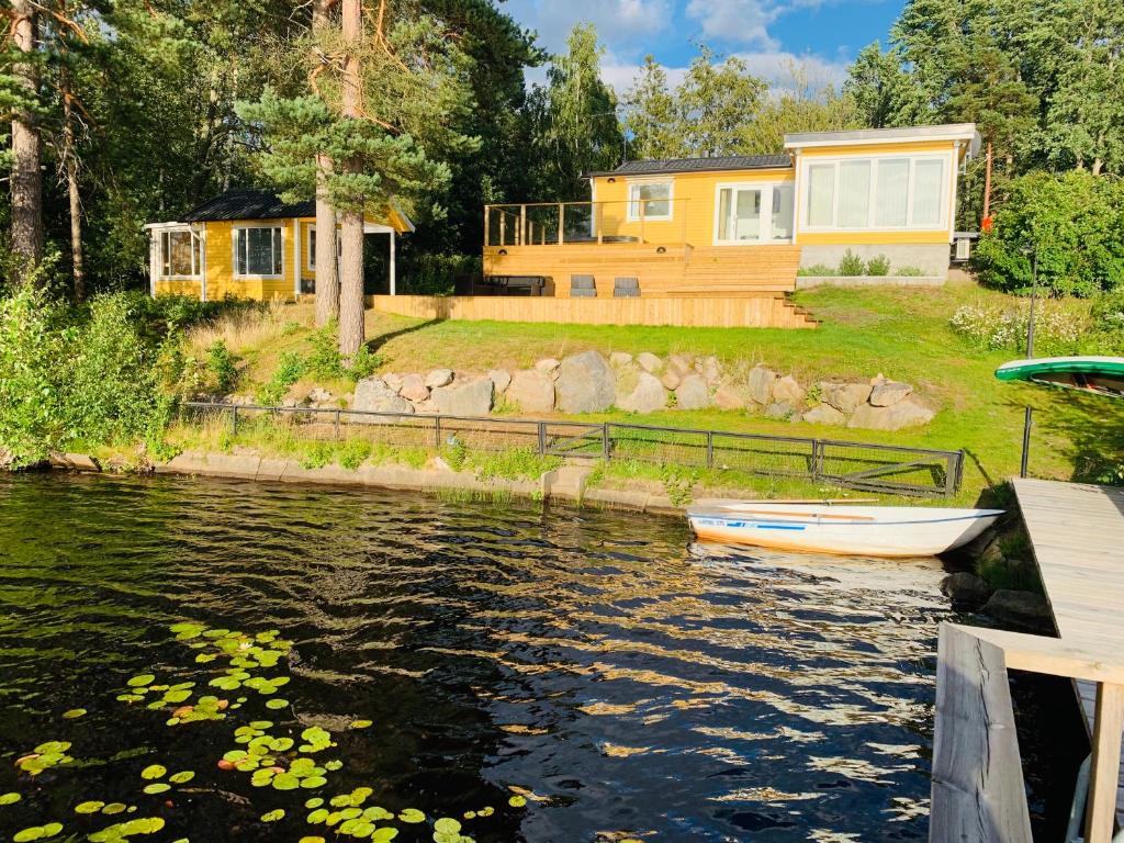 een huis en een boot voor een rivier bij Sjötomt Borshult in Diö