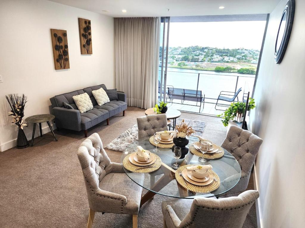 ブリスベンにあるSpacious River View Escape with Free Secure Park - 2BR, 2BA and Sofa Bedのガラスのテーブルと椅子のあるリビングルーム