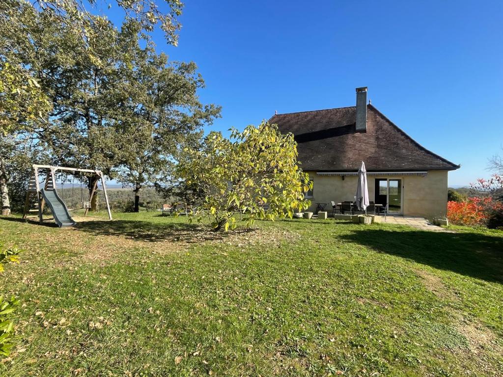 a house with a playground in front of a yard at Gîte "le haut des Poujades" in Reilhaguet