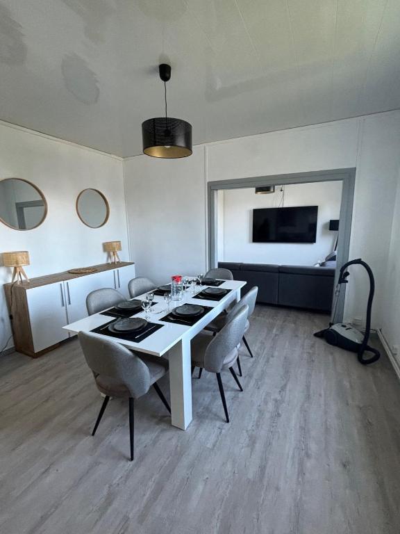 une salle à manger avec une table et des chaises blanches dans l'établissement les dunes proche plage jardin, à Urville-Nacqueville