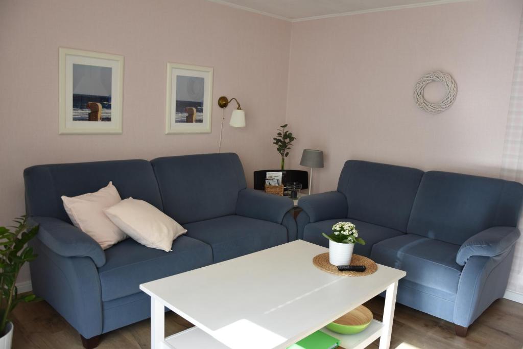 ein Wohnzimmer mit einem blauen Sofa und einem Tisch in der Unterkunft Bungalow Gartenzauber in Grube