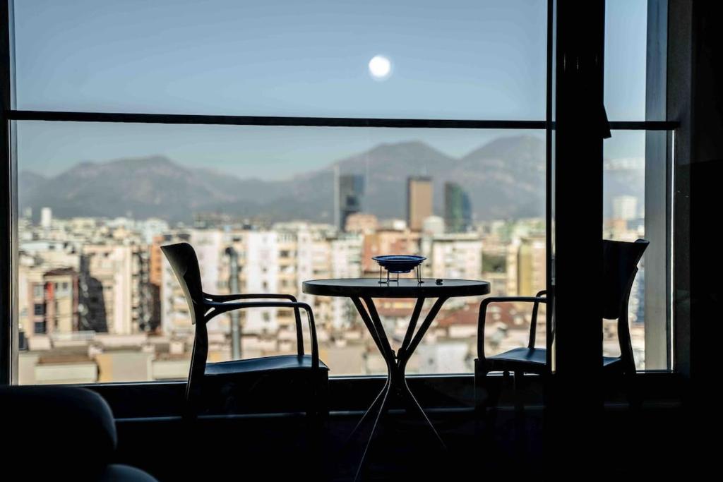 ein Tisch und zwei Stühle vor einem Fenster in der Unterkunft Tirana Hideaways , Breathtaking View & Free Parking in Tirana