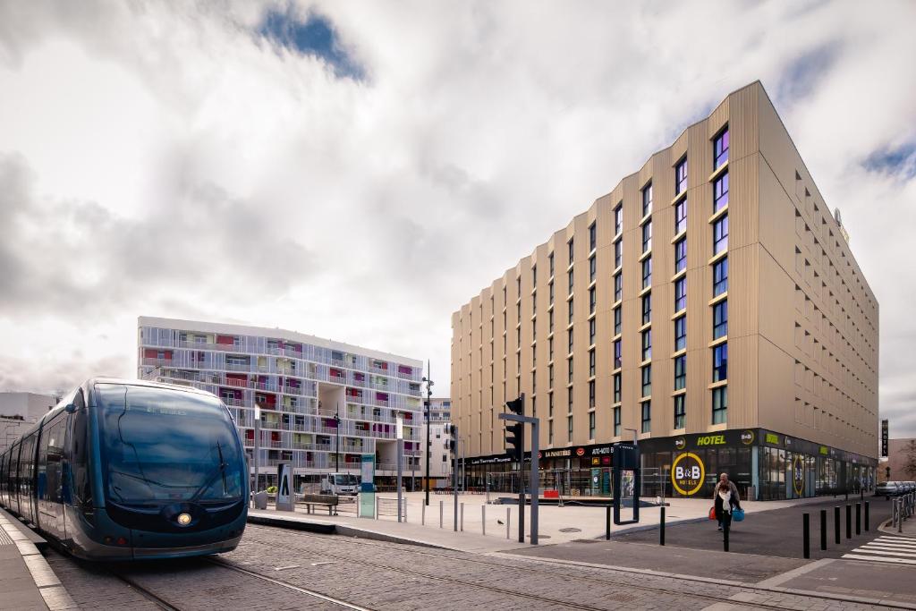 un train est sur la voie à proximité d'un bâtiment dans l'établissement B&B HOTEL Bordeaux Centre Bègles, à Bègles