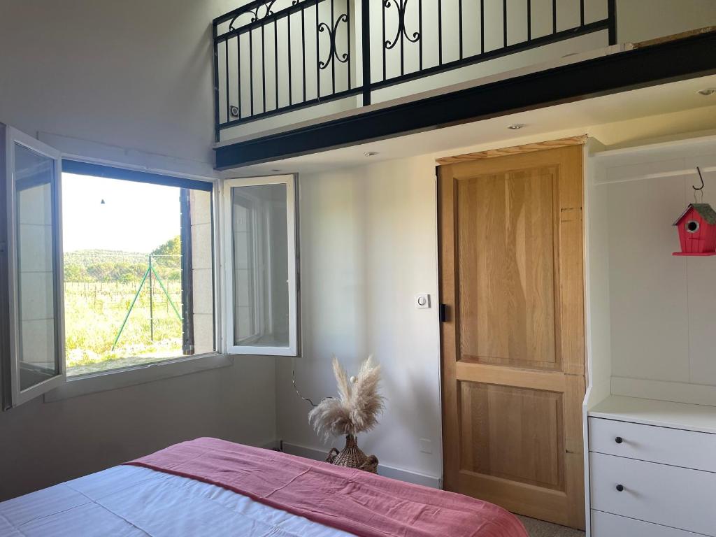 a bedroom with a bed with a wooden door and a window at Villa avec Pool House au cœur des vignes - Lubéron in La Tour-dʼAigues