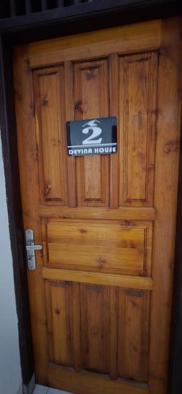 a wooden door with a sign on it at Devina House in Kuta