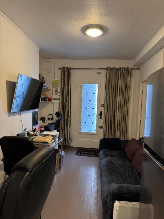 un salon avec un canapé, un bureau et une fenêtre dans l'établissement Charmant 2P Paris - Haut Parc Belleville, à Paris