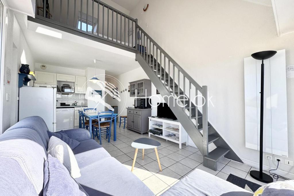 - un salon avec un canapé bleu et un escalier dans l'établissement Charmant T3 duplex - Bord de mer - Terrasse, à Quiberon