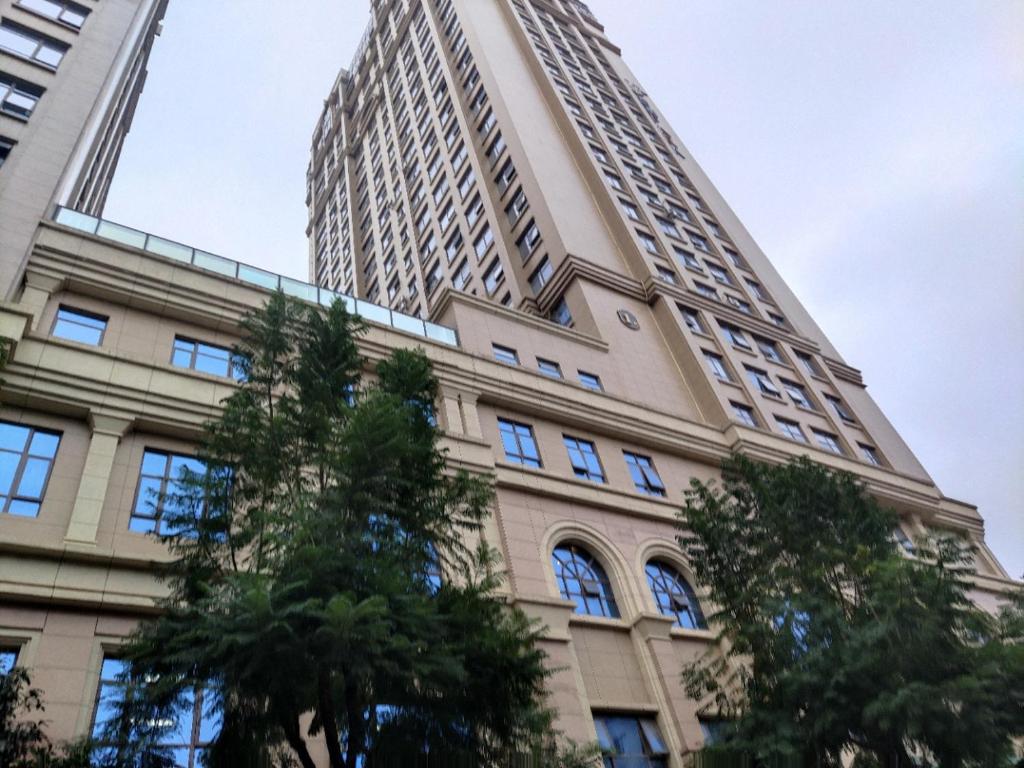 a tall building with trees in front of it at Smart Ruoqi B&B in Kunming