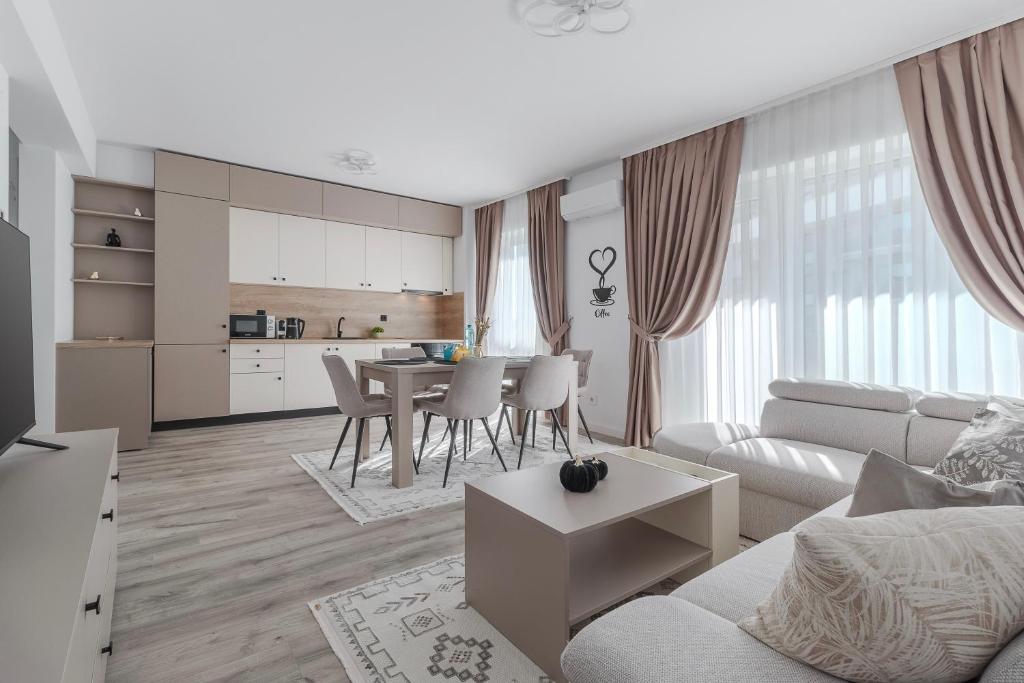 a white living room with a table and a kitchen at Cream Divine in Oradea