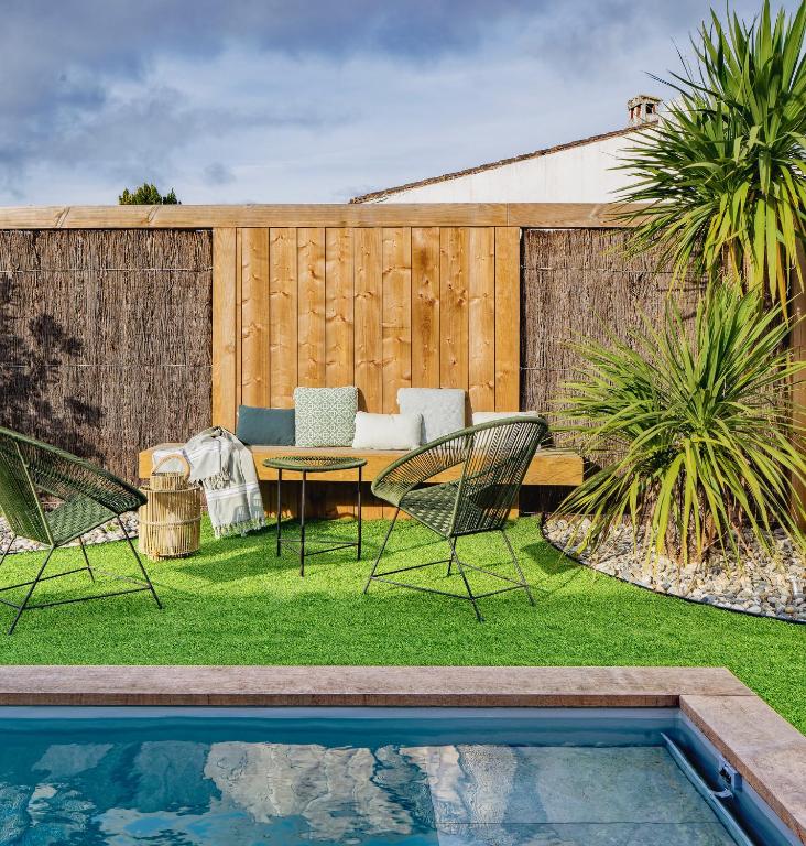une cour avec une piscine, des chaises et une table dans l'établissement Les Villas du Bois, au Bois-Plage-en-Ré