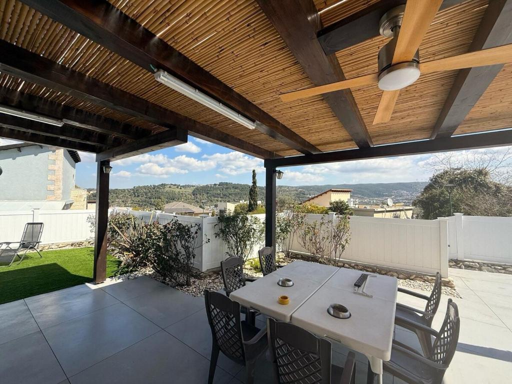 un patio con una mesa y sillas blancas y un techo de madera. en הבית של אסף - 3 וילות משפחתיות זהות, en H̱osen