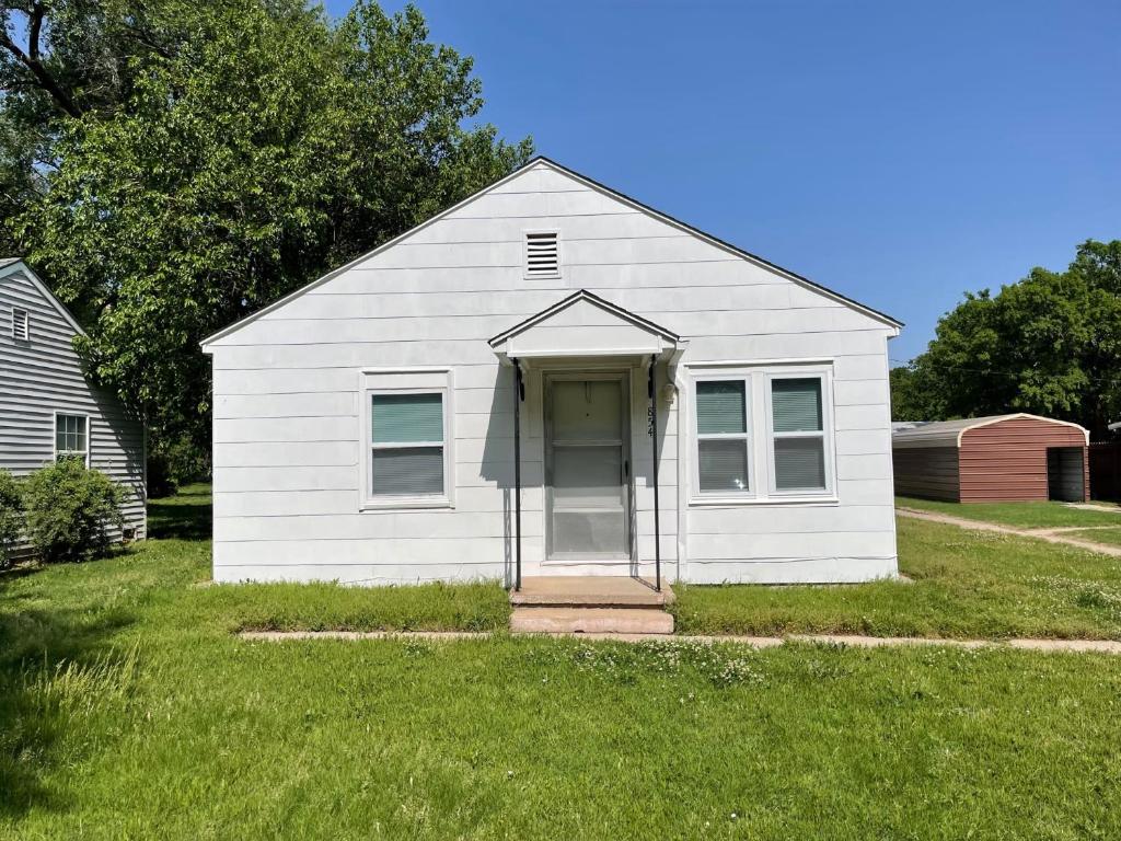 ein weißes Haus mit einer Tür in einem Hof in der Unterkunft Everything you need - 1 BR 1 BA WIFI SMART TV QN Bed Coffee in Wichita