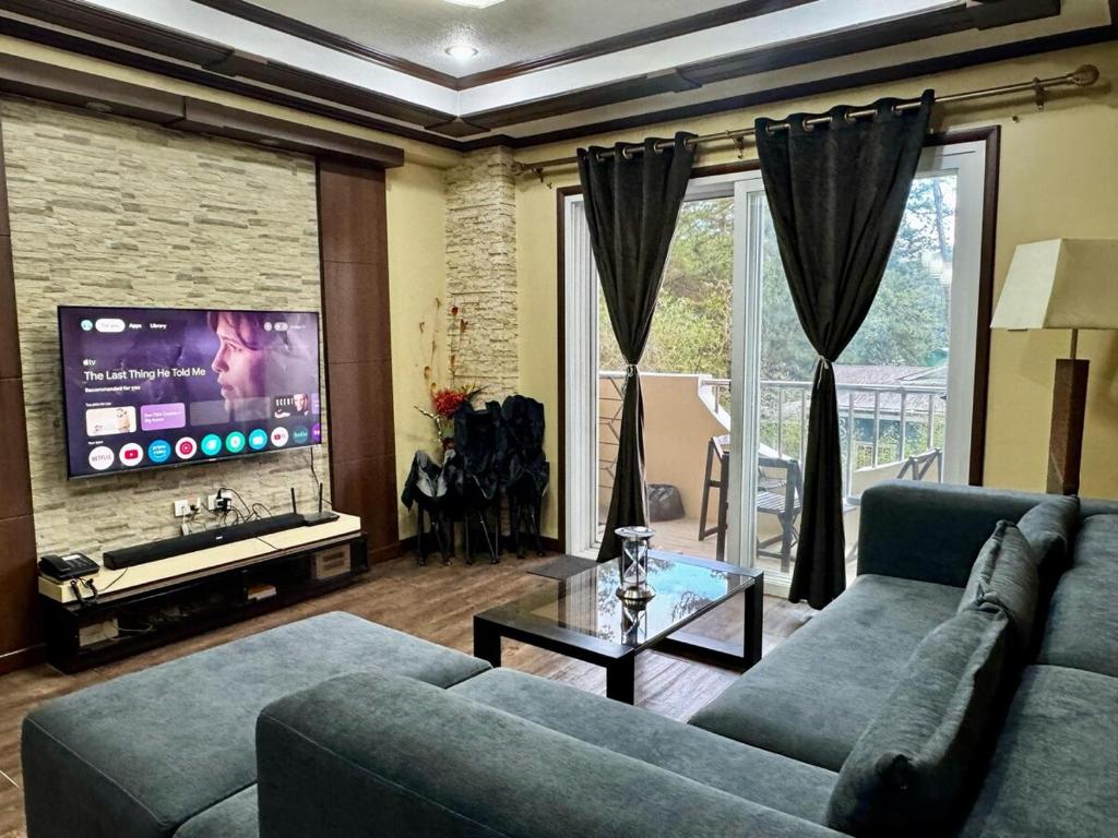 Una sala de estar con un sofá azul y un televisor en Ezwi's Staycation, en Baguio
