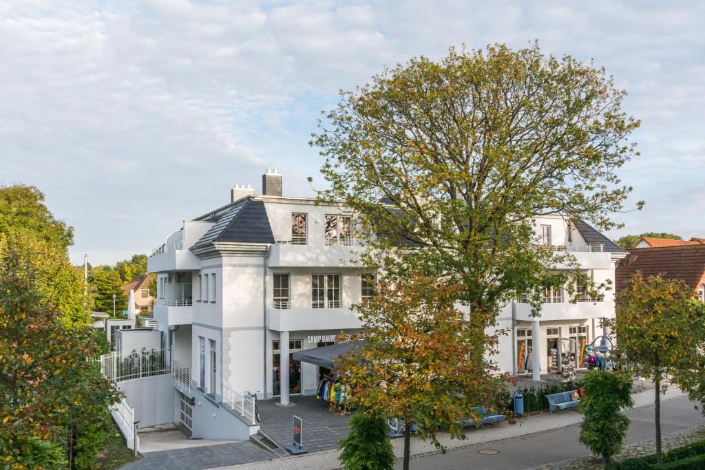 a white house with a tree in front of it at Victoria Luna Penthouse No 10 Strandstrstr48 in Zingst